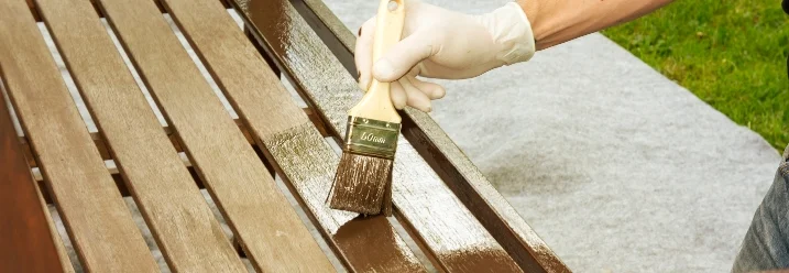 Person streicht Holzbank